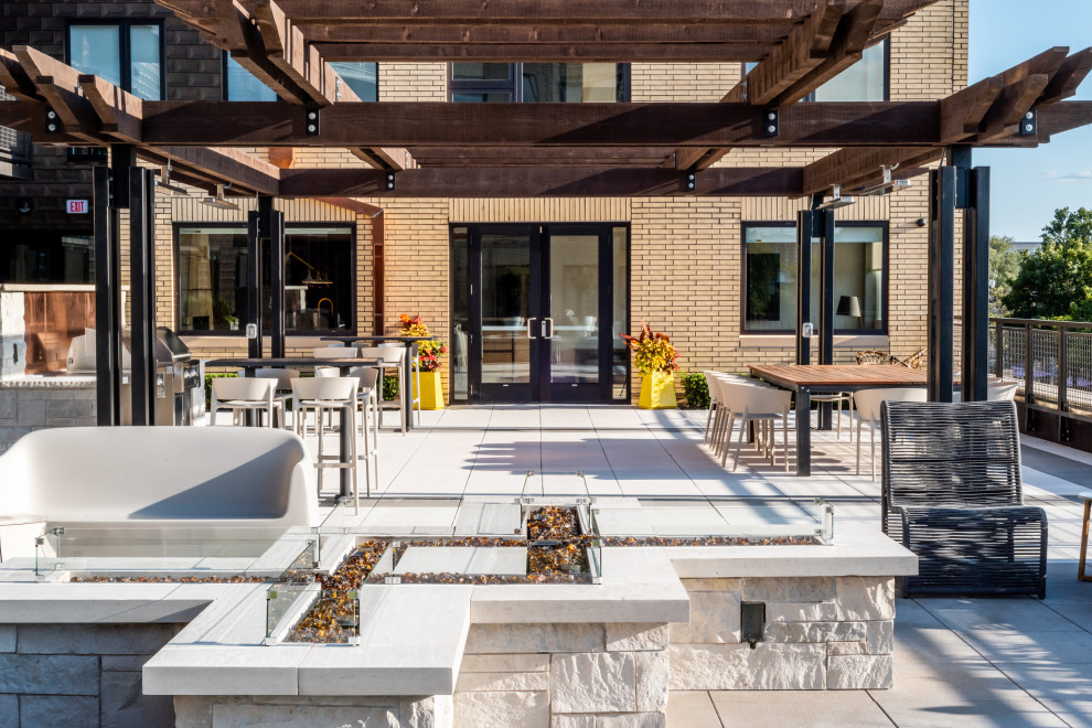 Photo of a modern courtyard patio in Minneapolis with with fireplace, natural stone pavers and a pergola.