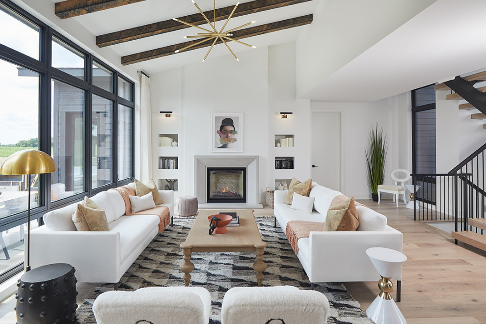 Large contemporary open plan living room in Grand Rapids with white walls, light hardwood flooring, a standard fireplace, a concrete fireplace surround and exposed beams.