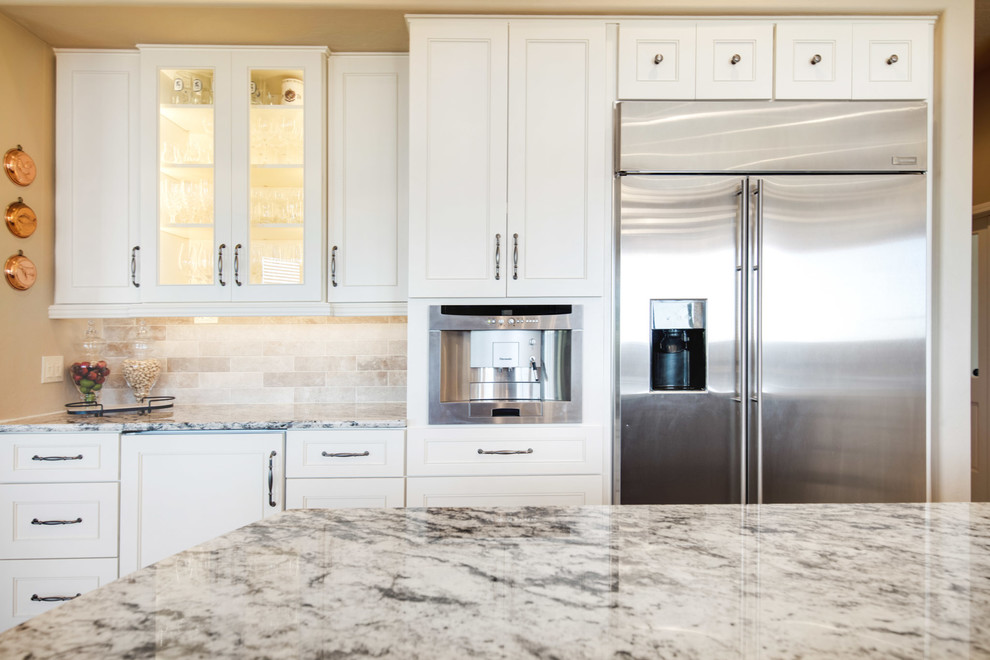 Open concept kitchen - large transitional u-shaped travertine floor and beige floor open concept kitchen idea in Phoenix with a farmhouse sink, recessed-panel cabinets, white cabinets, granite countertops, gray backsplash, porcelain backsplash, stainless steel appliances, an island and multicolored countertops