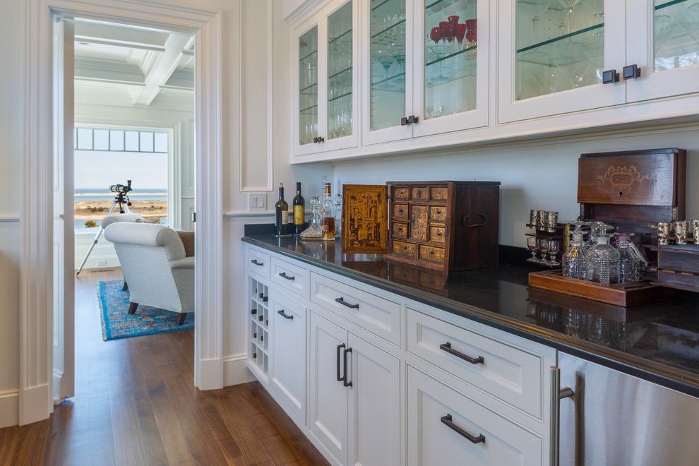This is an example of a large beach style galley kitchen pantry in Boston with beaded inset cabinets, white cabinets, dark hardwood floors and brown floor.