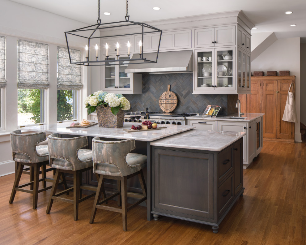 This is an example of a transitional kitchen in Philadelphia with recessed-panel cabinets, grey cabinets, grey splashback, stainless steel appliances, medium hardwood floors, with island, brown floor and grey benchtop.