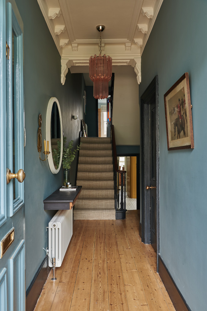 Design ideas for a mid-sized traditional entryway in London with blue walls and medium hardwood floors.