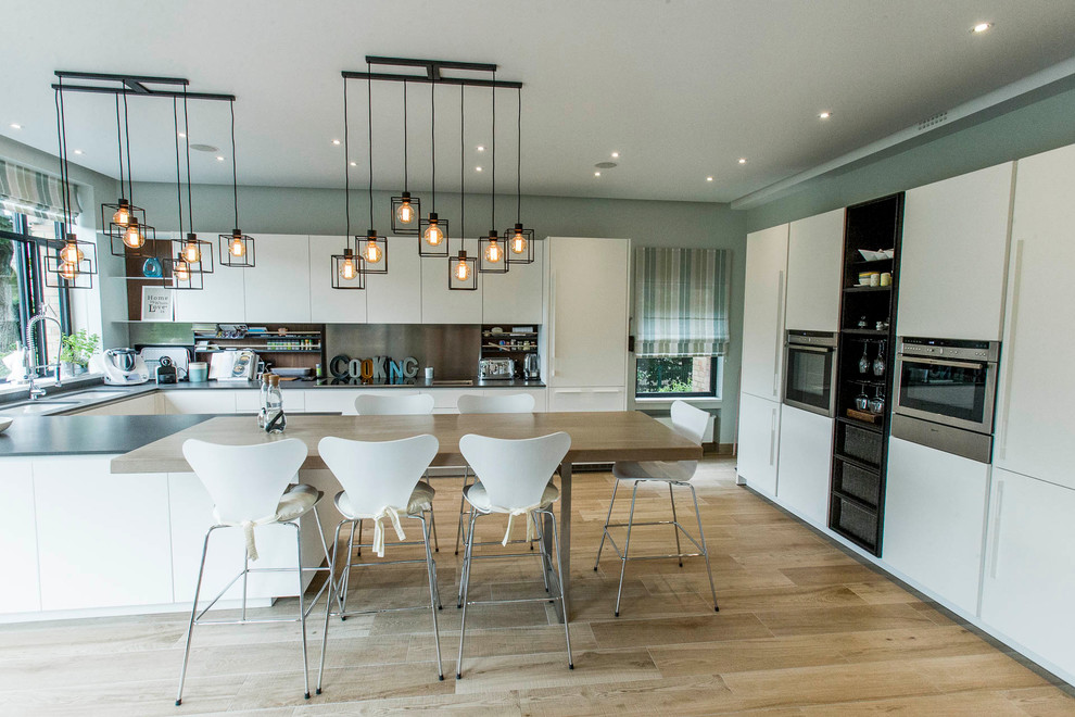 Idées déco pour cuisine américaine in U With un évier 2 bacs, des portes de placard blanches, un plan de travail en quartz modifié, une crédence grise, une crédence en quartz modifié, un électroménager en acier inoxydable, îlot, un sol marron, un plan de travail gris and parquet clair.
