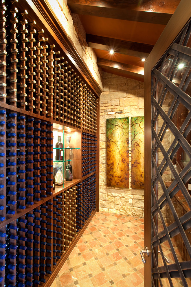 Photo of a mediterranean wine cellar in Austin with storage racks and orange floor.