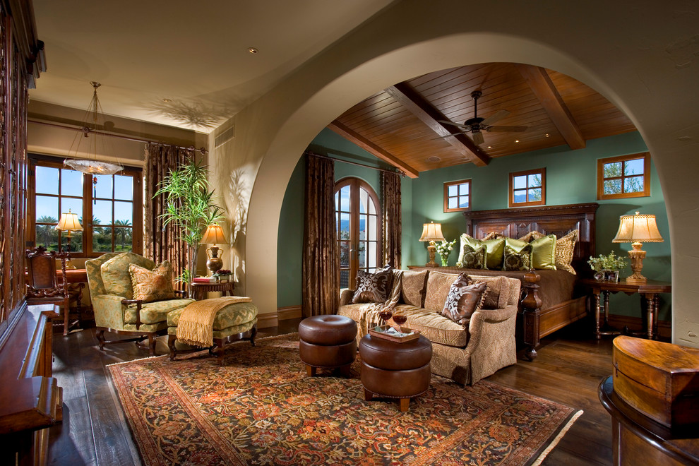 Photo of a mediterranean bedroom in Orange County with green walls, brown floor and dark hardwood floors.