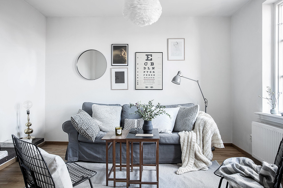 Mid-sized scandinavian formal enclosed living room in Gothenburg with white walls, light hardwood floors and no tv.