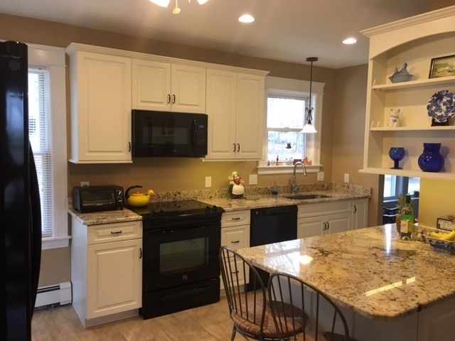 Mid-sized transitional galley porcelain tile eat-in kitchen photo in Boston with an undermount sink, raised-panel cabinets, white cabinets, granite countertops, black appliances and an island
