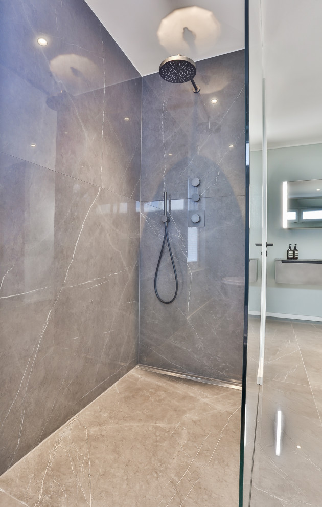 This is an example of a mid-sized modern master bathroom in Frankfurt with grey cabinets, a freestanding tub, a curbless shower, a wall-mount toilet, gray tile, marble, green walls, marble floors, an integrated sink, glass benchtops, grey floor, an open shower, grey benchtops, an enclosed toilet, a single vanity, a floating vanity, recessed and wallpaper.