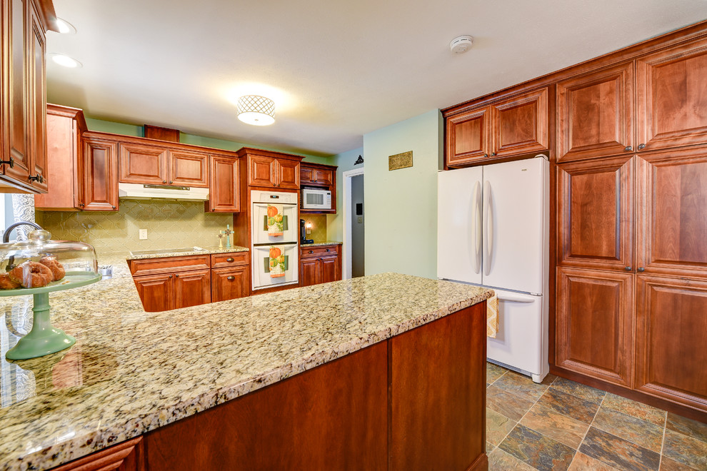 Photo of a medium sized classic u-shaped kitchen/diner in Other with a submerged sink, raised-panel cabinets, medium wood cabinets, granite worktops, beige splashback, porcelain splashback, white appliances, slate flooring and a breakfast bar.