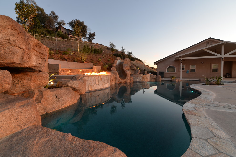 Photo of a large transitional backyard custom-shaped pool in San Diego with a water slide and concrete pavers.