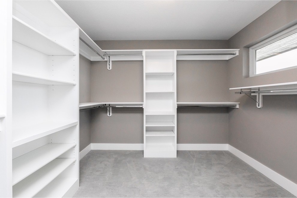 This is an example of a mid-sized modern women's walk-in wardrobe in Other with white cabinets, carpet and grey floor.