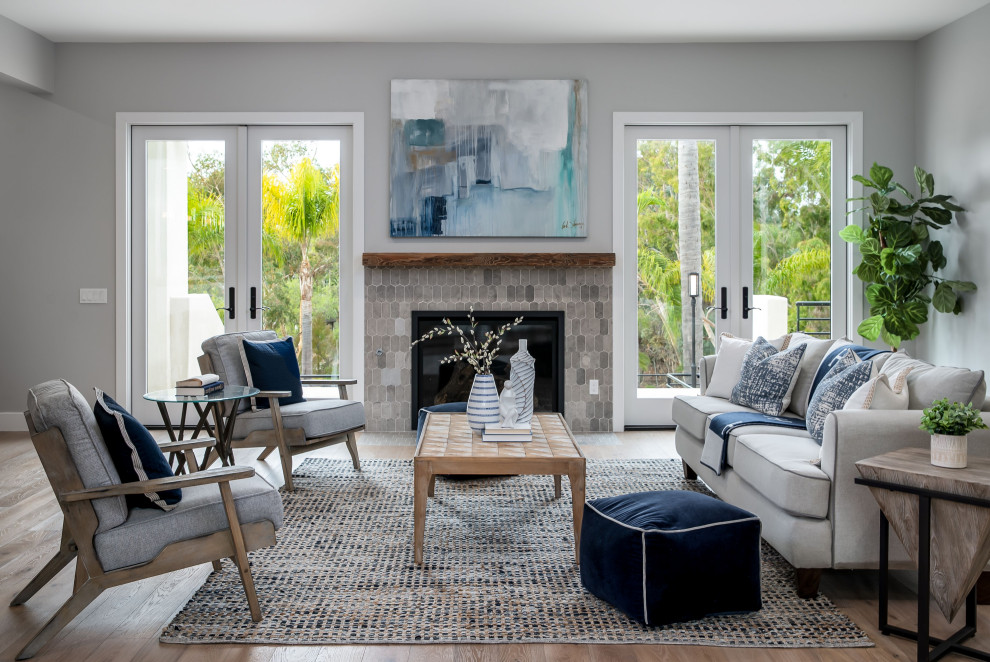 Design ideas for an expansive mediterranean enclosed living room in San Diego with a library, grey walls, light hardwood floors, a standard fireplace, a tile fireplace surround, a wall-mounted tv and beige floor.