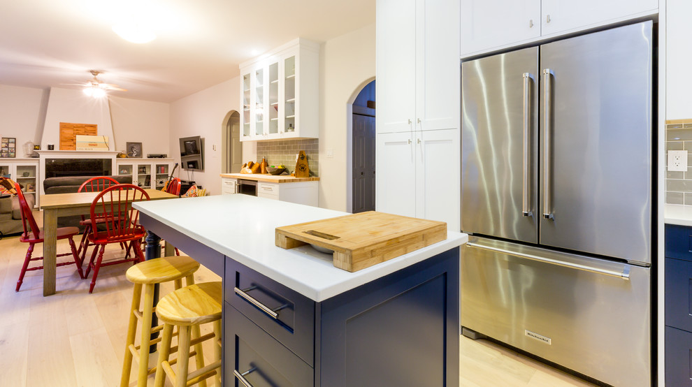 Open concept kitchen - large transitional u-shaped light wood floor open concept kitchen idea with a farmhouse sink, shaker cabinets, blue cabinets, quartz countertops, gray backsplash, glass tile backsplash, stainless steel appliances, an island and turquoise countertops