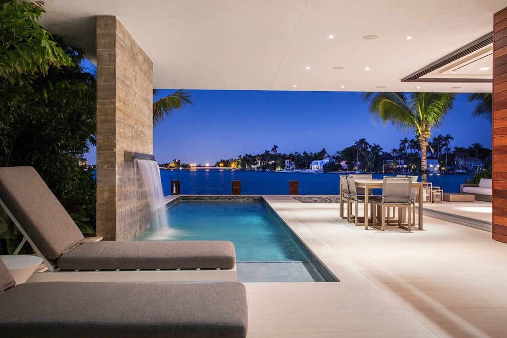 Beach style rectangular pool in Miami with a water feature.