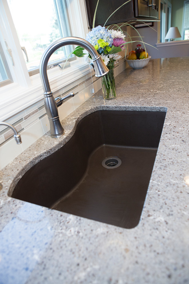Example of a mid-sized transitional u-shaped light wood floor enclosed kitchen design in Chicago with an undermount sink, raised-panel cabinets, dark wood cabinets, quartz countertops, beige backsplash, ceramic backsplash, stainless steel appliances and an island