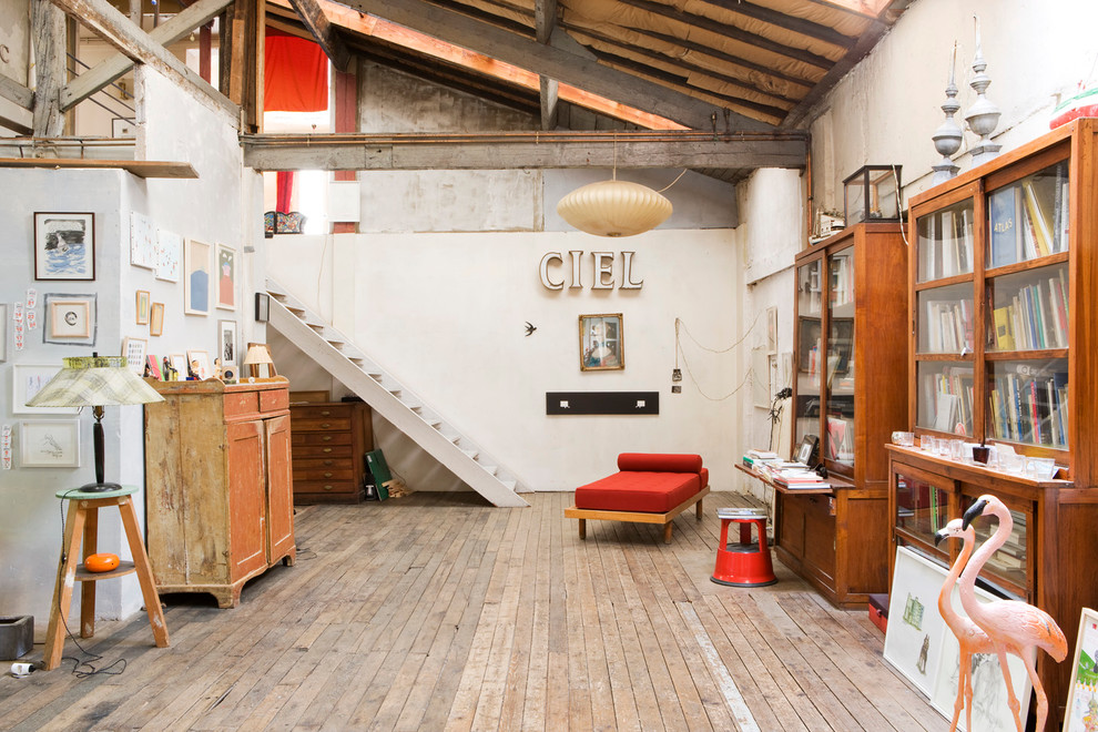 Inspiration pour une grande salle de séjour urbaine fermée avec une bibliothèque ou un coin lecture, un mur blanc, un sol en bois brun et aucun téléviseur.