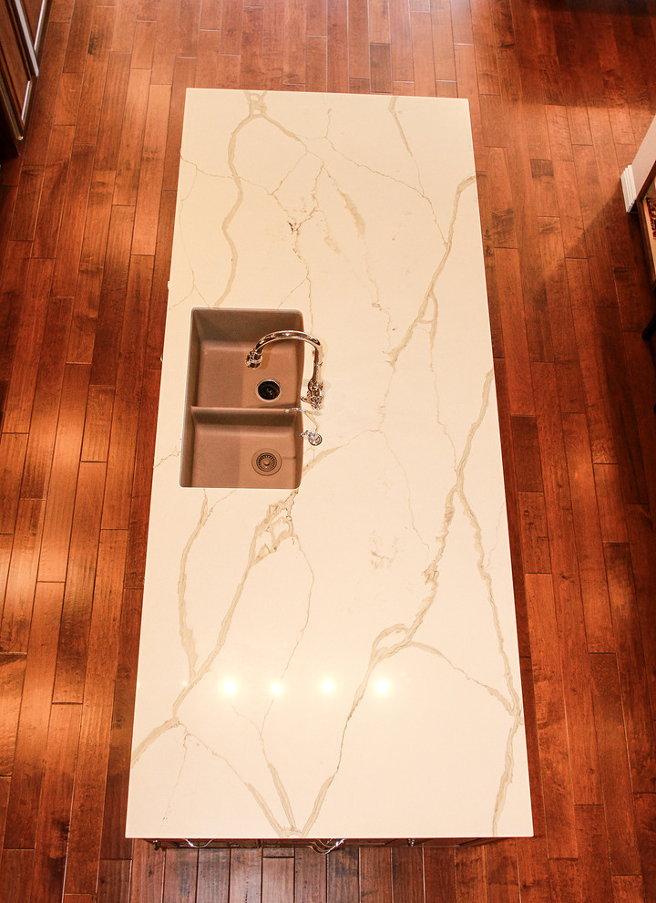 Inspiration for a large transitional medium tone wood floor and brown floor kitchen remodel in Orange County with a double-bowl sink, raised-panel cabinets, brown cabinets, quartzite countertops, white backsplash, stone tile backsplash, stainless steel appliances and two islands