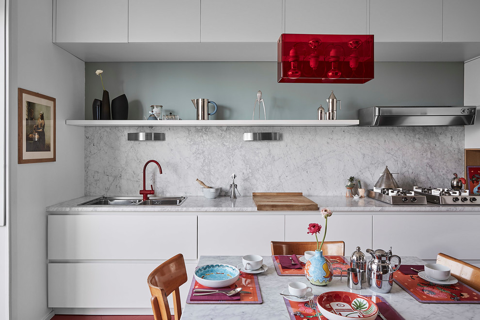 This is an example of a mid-sized contemporary single-wall eat-in kitchen in Milan with a double-bowl sink, flat-panel cabinets, white cabinets, marble benchtops, white splashback, marble splashback, no island, panelled appliances and red floor.