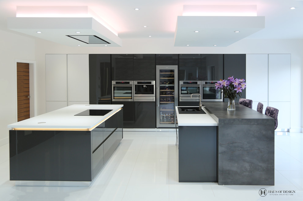 Inspiration for a large modern single-wall open plan kitchen with an integrated sink, flat-panel cabinets, black cabinets, composite countertops, black appliances, porcelain flooring, multiple islands, white floors and white worktops.