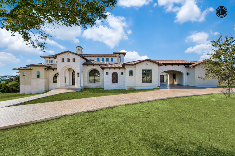 Expansive mediterranean two-storey white house exterior in Austin with stone veneer, a tile roof and a red roof.