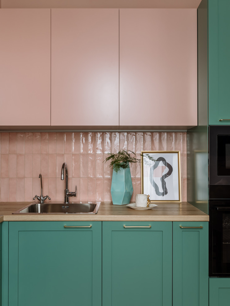 Свежая идея для дизайна: угловая кухня-гостиная среднего размера в стиле ретро с накладной мойкой, зелеными фасадами, розовым фартуком, фартуком из керамической плитки и черной техникой без острова - отличное фото интерьера
