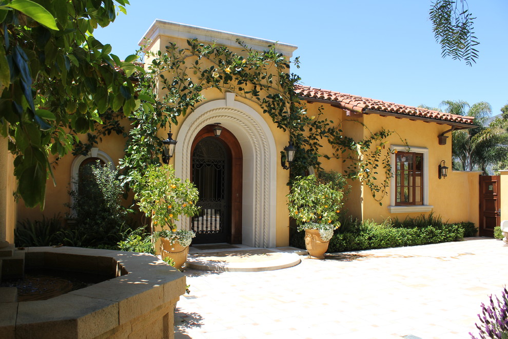 This is an example of a large mediterranean one-storey stucco yellow exterior in Santa Barbara with a hip roof.