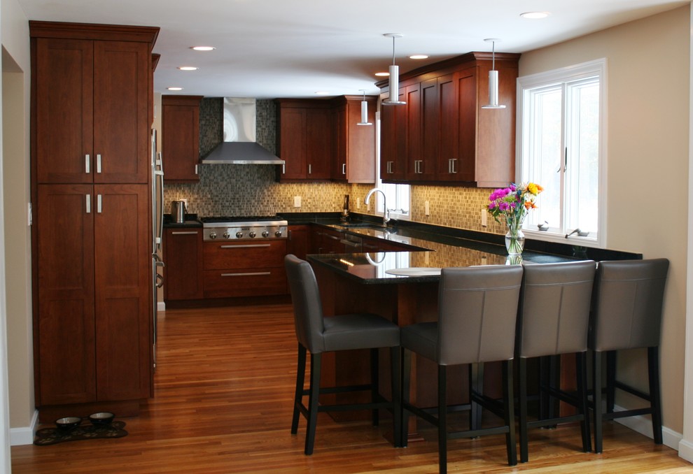 Example of a large transitional u-shaped medium tone wood floor eat-in kitchen design in Boston with an undermount sink, shaker cabinets, medium tone wood cabinets, granite countertops, beige backsplash, glass tile backsplash, stainless steel appliances and a peninsula