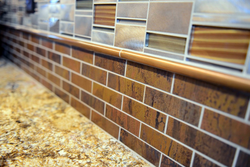 Example of a large mountain style dark wood floor home design design with an undermount sink, raised-panel cabinets, light wood cabinets, granite countertops, metallic backsplash, metal backsplash, stainless steel appliances and an island