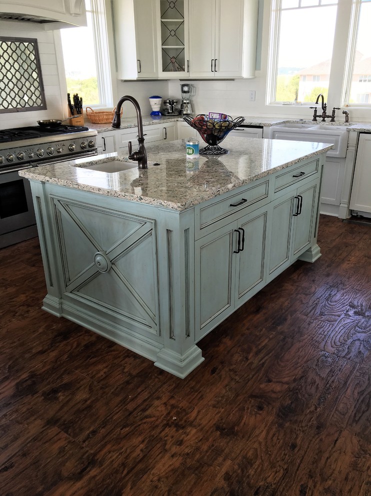 Inspiration for a large coastal u-shaped light wood floor kitchen pantry remodel with a farmhouse sink, flat-panel cabinets, beige cabinets, recycled glass countertops, ceramic backsplash, stainless steel appliances and two islands