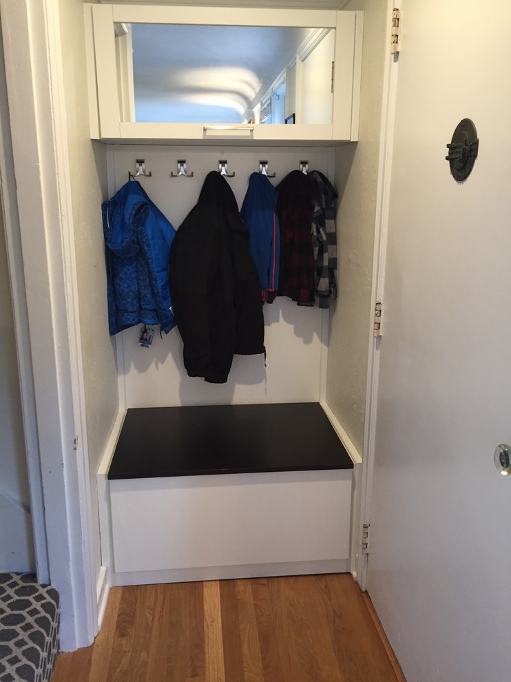 Example of a small transitional medium tone wood floor mudroom design with white walls