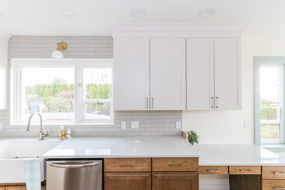 Small country galley separate kitchen in Seattle with a farmhouse sink, shaker cabinets, quartz benchtops, grey splashback, porcelain splashback, stainless steel appliances, vinyl floors and white benchtop.