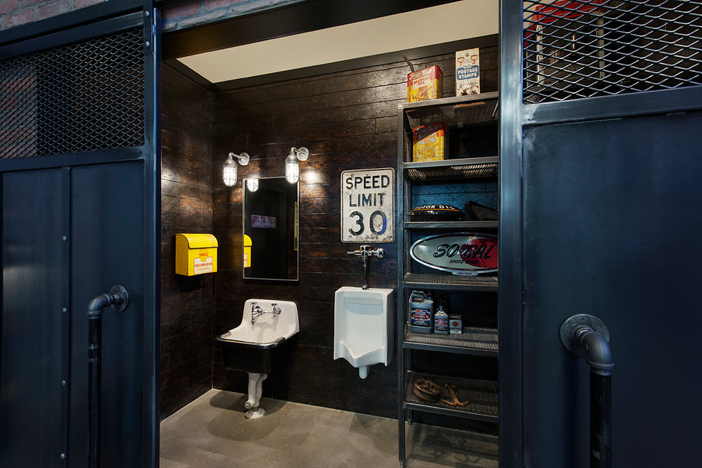This is an example of a mid-sized industrial bathroom in Calgary with open cabinets, an urinal, brown walls, concrete floors and a pedestal sink.