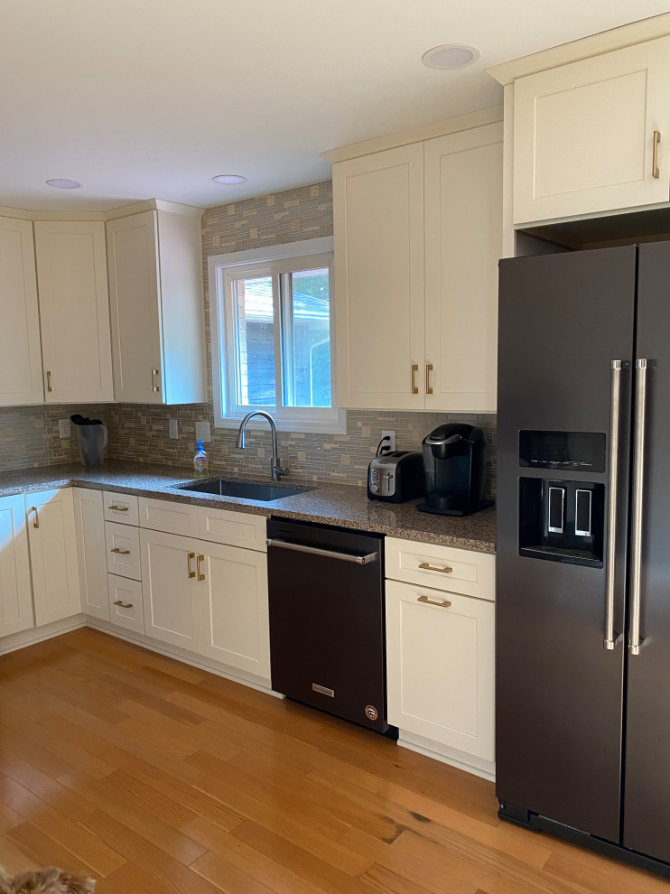 Design ideas for a mid-sized traditional l-shaped separate kitchen in Cleveland with a single-bowl sink, shaker cabinets, white cabinets, quartz benchtops, green splashback, mosaic tile splashback, black appliances, light hardwood floors, no island, beige floor and grey benchtop.