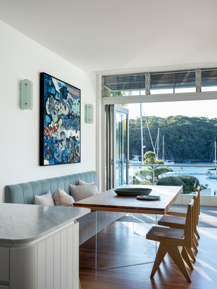 Inspiration for a beach style dining room in Sydney with white walls, medium hardwood floors and brown floor.
