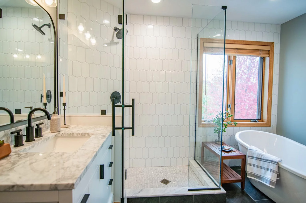This is an example of a mid-sized transitional master bathroom in Minneapolis with shaker cabinets, white cabinets, a freestanding tub, white tile, ceramic tile, blue walls, a drop-in sink, engineered quartz benchtops, black floor, a hinged shower door, white benchtops, a double vanity and a freestanding vanity.
