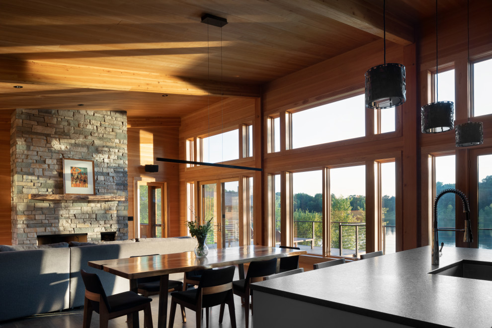 Стильный дизайн: кухня-столовая среднего размера с коричневыми стенами, светлым паркетным полом, двусторонним камином, фасадом камина из камня, коричневым полом, деревянным потолком и деревянными стенами - последний тренд