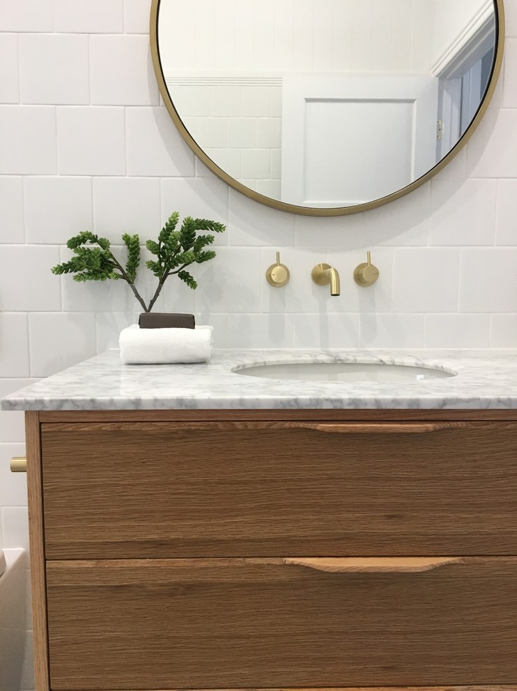 Inspiration for a mid-sized modern 3/4 bathroom in Brisbane with furniture-like cabinets, light wood cabinets, a freestanding tub, an open shower, a one-piece toilet, white tile, ceramic tile, white walls, laminate floors, an undermount sink, marble benchtops, multi-coloured floor, an open shower and white benchtops.