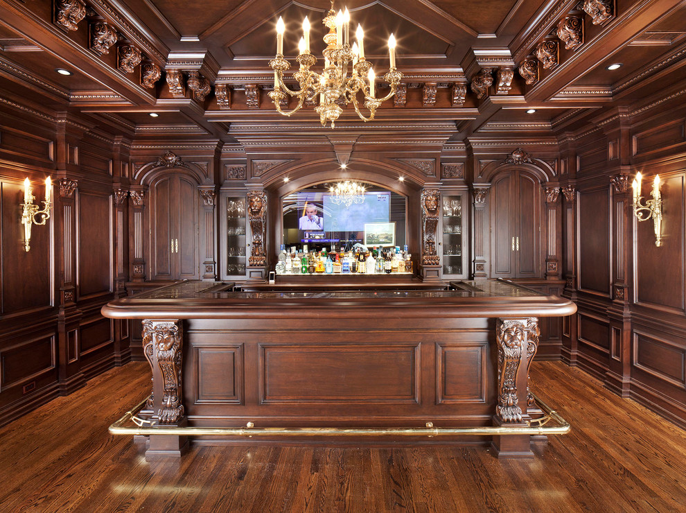 Photo of a large traditional u-shaped seated home bar in DC Metro with an undermount sink, raised-panel cabinets, brown cabinets, granite benchtops, medium hardwood floors and brown floor.