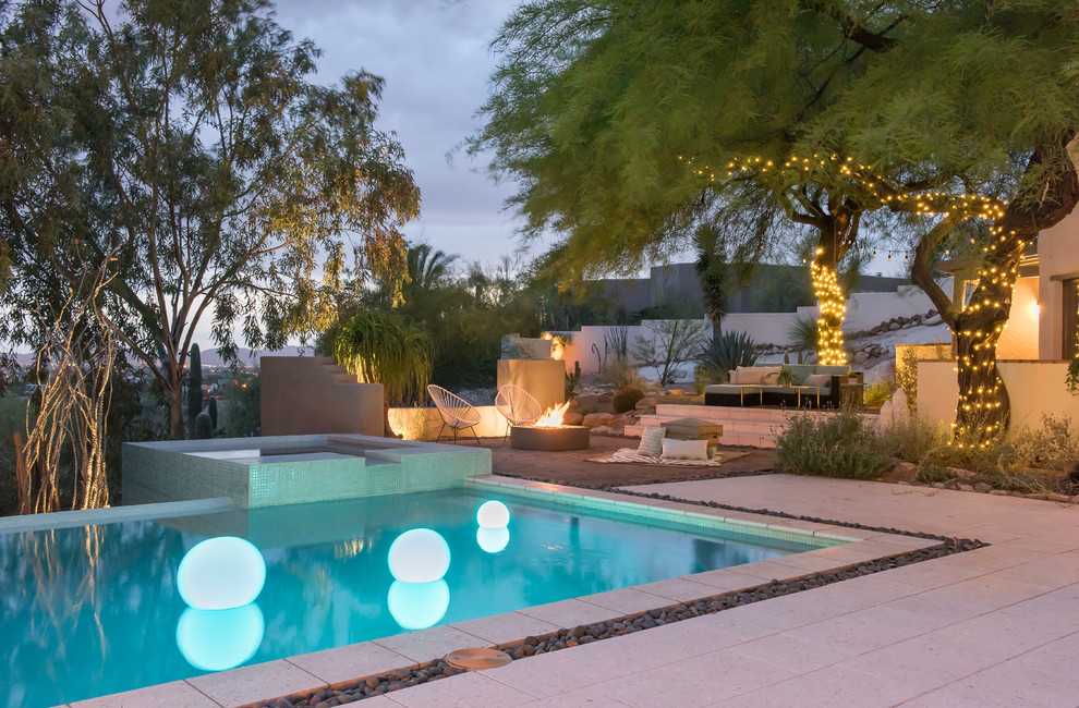 This is an example of a large contemporary backyard rectangular infinity pool in Phoenix with a hot tub and decomposed granite.