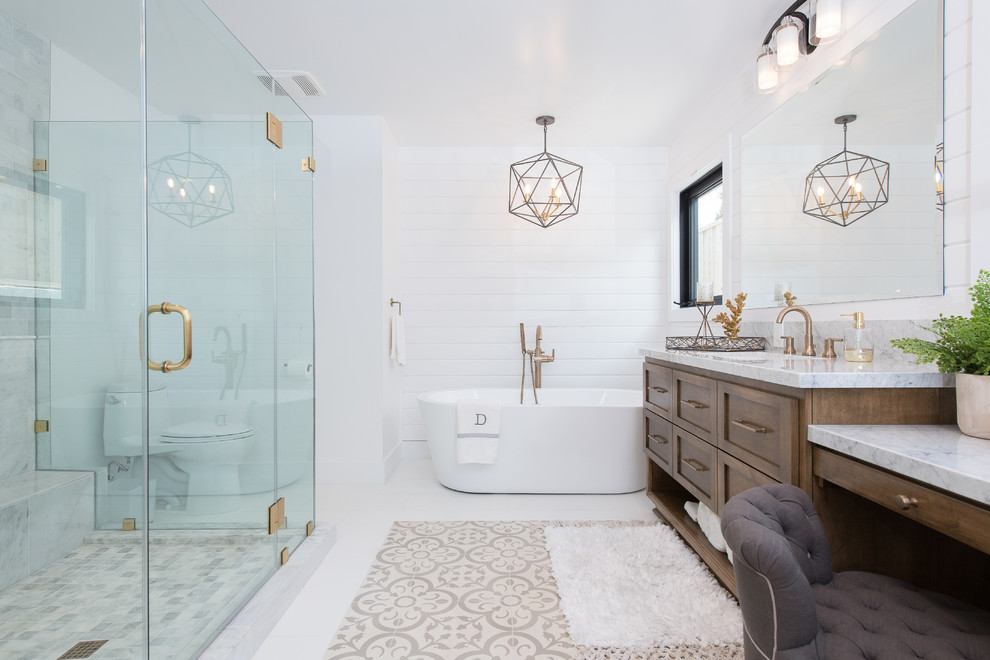 This is an example of a large country master bathroom in Orange County with shaker cabinets, brown cabinets, a freestanding tub, a one-piece toilet, white tile, subway tile, white walls, an integrated sink, granite benchtops, white floor, a hinged shower door and white benchtops.