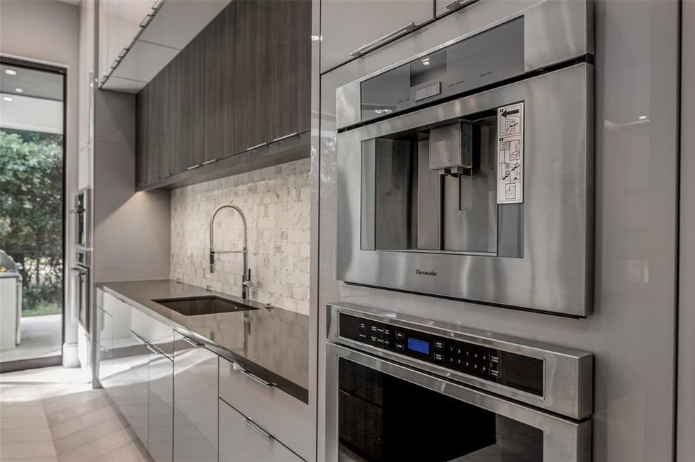 Inspiration for a contemporary l-shaped kitchen in Houston with flat-panel cabinets, grey cabinets, marble benchtops, grey splashback, marble splashback, stainless steel appliances, travertine floors, grey benchtop and grey floor.