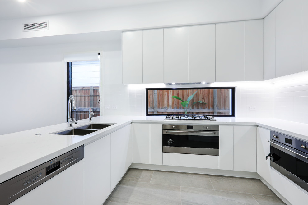Inspiration for a contemporary kitchen in Gold Coast - Tweed with quartz benchtops, white splashback, stainless steel appliances and white benchtop.