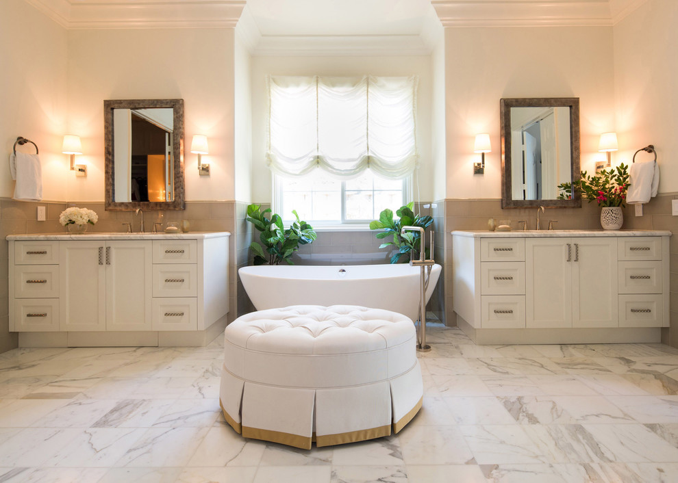 Inspiration for a large transitional master bathroom in Los Angeles with shaker cabinets, white cabinets, a freestanding tub, gray tile, glass tile, white walls, marble floors, an undermount sink and marble benchtops.