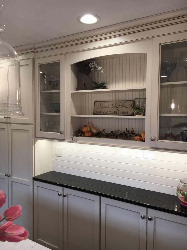Eat-in kitchen - large transitional medium tone wood floor and brown floor eat-in kitchen idea with an undermount sink, flat-panel cabinets, white cabinets, granite countertops, white backsplash, porcelain backsplash, stainless steel appliances and an island