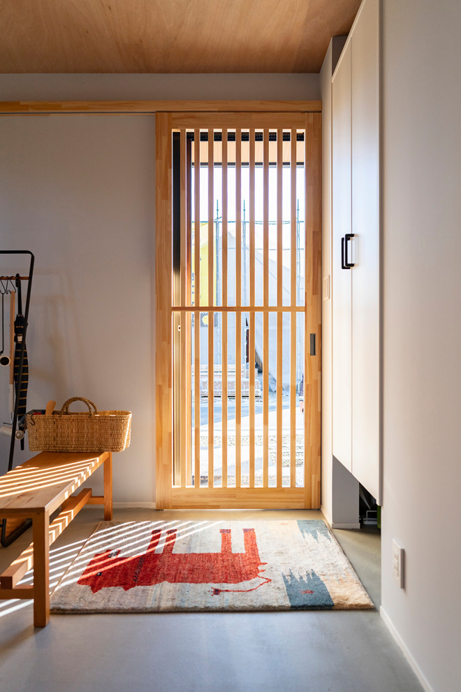 Свежая идея для дизайна: маленькая входная дверь в современном стиле с серыми стенами, бетонным полом, раздвижной входной дверью, входной дверью из светлого дерева, серым полом, деревянным потолком и стенами из вагонки для на участке и в саду - отличное фото интерьера