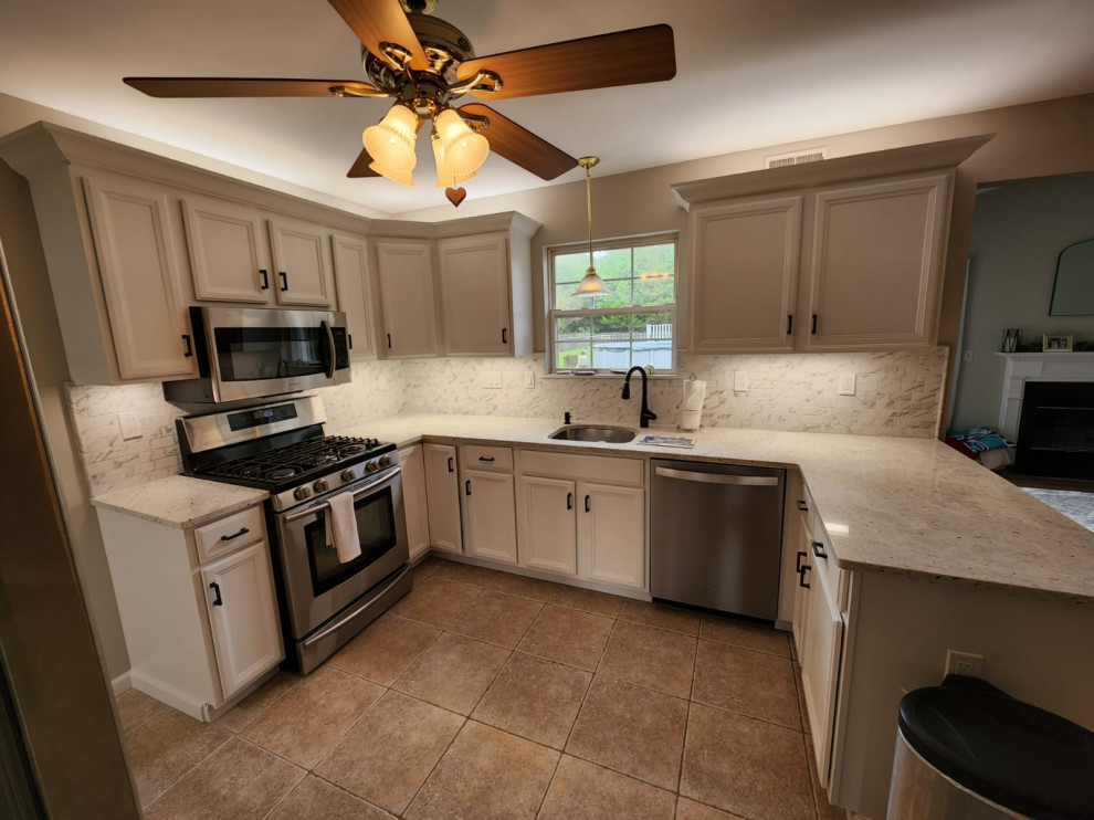 Mid-sized minimalist l-shaped porcelain tile and brown floor eat-in kitchen photo in New York with an undermount sink, flat-panel cabinets, white cabinets, granite countertops, white backsplash, ceramic backsplash, stainless steel appliances, a peninsula and white countertops
