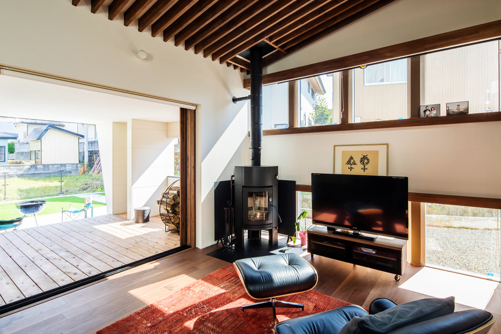 Photo of a contemporary open concept living room in Other with a wood stove, a freestanding tv, white walls, medium hardwood floors and brown floor.