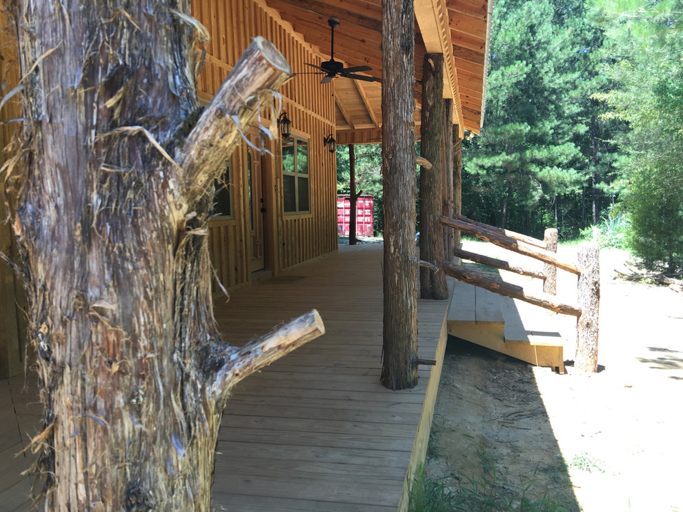 This is an example of a large rustic front porch design with decking and a roof extension.