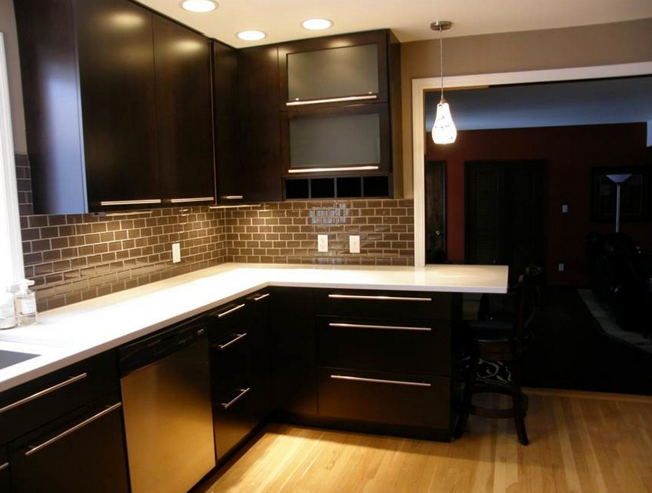 Example of a mid-sized minimalist u-shaped light wood floor enclosed kitchen design with an undermount sink, flat-panel cabinets, dark wood cabinets, quartz countertops, brown backsplash, ceramic backsplash, stainless steel appliances and a peninsula