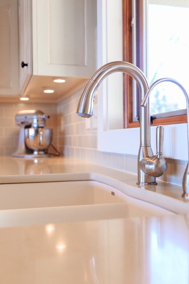 Kitchen - transitional l-shaped vinyl floor kitchen idea in Minneapolis with an undermount sink, raised-panel cabinets, white cabinets, quartz countertops, beige backsplash, ceramic backsplash, paneled appliances and an island